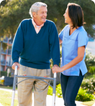 Caregiver assisting an old man to walk